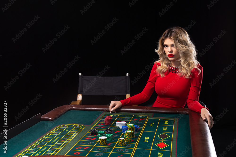 Young blonde woman wearing beautiful red dress is playing roulette in the  casino Stock Photo | Adobe Stock