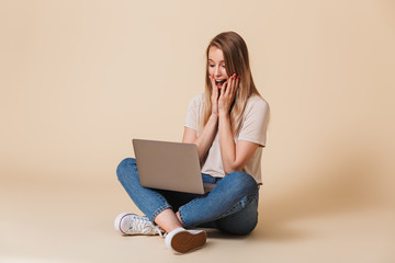 Wall Mural - Portrait of an excited casual girl looking at laptop computer