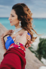 Wall Mural - Groom holds tender hand of Hindu bride covered with henna tattoo