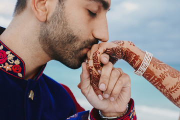 Wall Mural - Groom holds tender hand of Hindu bride covered with henna tattoo