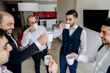 Wall Mural - Hindu men drink coffee with groom in a hotel room