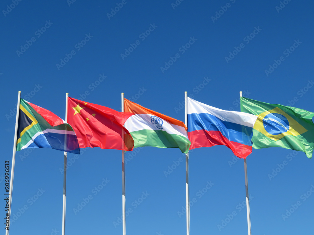 Waving flags of the BRICS countries against the blue sky. The summit of Brazil, Russia, India, China and South Africa