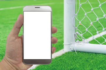 Poster - Hand holding smartphone with soccer field background.