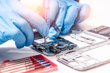 Wall Mural - The abstract image of the technician assembling inside of smartphone by screwdriver in the lab. the concept of computer hardware, mobile phone, electronic, repairing, upgrade and technology.