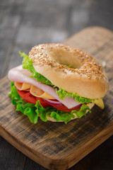 Wall Mural - Sesame bagel sandwich with lettuce, tomato, yellow cheese and ham.