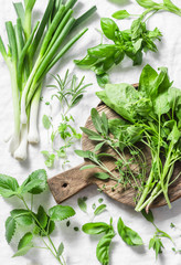 Garden herbs - spinach, basil, thyme, rosemary, sage, mint, onion, garlic on a light background, top view. Fresh food ingredients. Flat lay