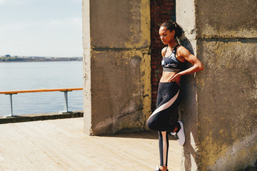 Wall Mural - Woman leaning a wall, resting after physical activity