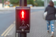 © Paul Rushton - push button wait for signal traffic light control with bright stop man illuminated at pedestrian crossing and woman walking past