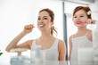 © Yakobchuk Olena - Close up portrait of beautiful mother and daughter brushing teeth. They are happy and joyful in the morning. They are looking at themselves in the mirror and smiling