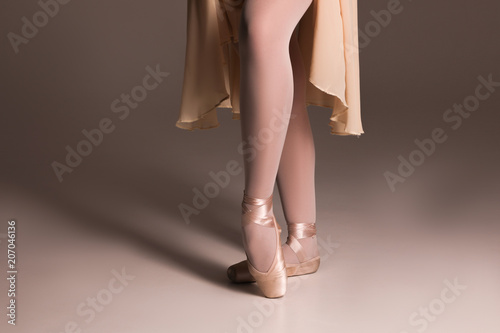 Step up! Close up picture of the feet of young ballerina wearing the beige  ballet shoes and standing in pointe position. - Buy this stock photo and  explore similar images at Adobe