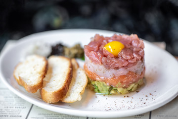 Wall Mural - fresh tuna, salmon and langoustine tartar with lime, avocado and sesame close-up on a plate. horizontal