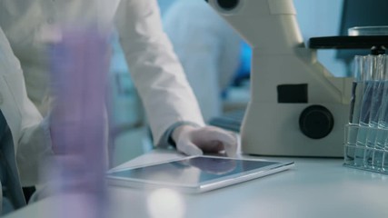 Wall Mural - close-up of life scientists in a laboratory using a tablet discussing the results of the research th