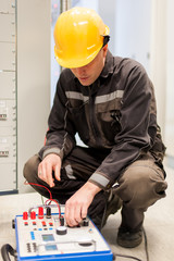Wall Mural - electrician engineer tests system with relay test set equipment