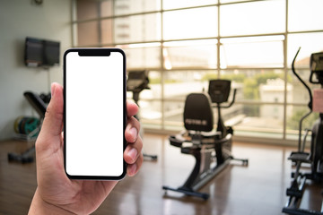 Poster - young man hand holding smartphone in gym to fitness phone fitness exercise concept