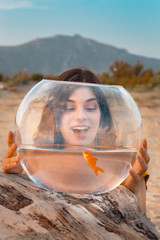 Happy woman watching golfish inside fishbowl