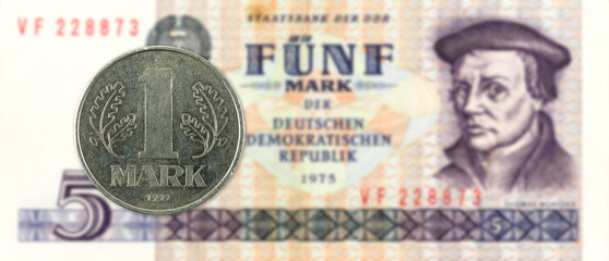 1 mark coin against historic 5 east german mark bank note