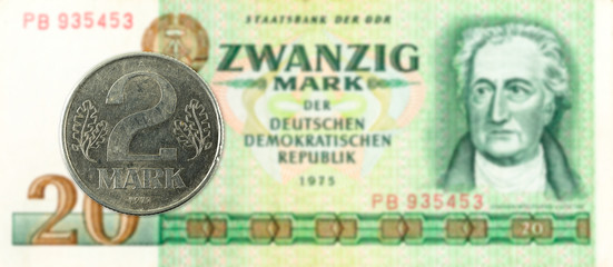 2 mark coin against historic 20 east german mark bank note