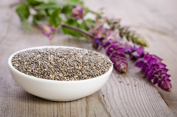 Chia seed healthy superfood in bowl with flower over wooden table