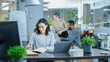 © Gorodenkoff - Busy International Office, Beautiful Hispanic Woman Working at Her Desk on a Laptop, in the Background Her Coworkers Have Work Related Conversations. Stylish Office with Bright Young People.