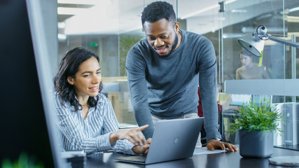 In the Busy Corporate Office Male and Female Have Work Related Discussion, Using Personal Computer. In the Background Creative Young People Working.