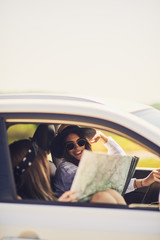 Wall Mural - Two young women having fun on road trip,checking map.