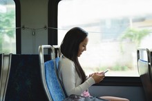 Woman Using Mobile Phone While Travelling In Bus