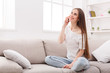© Prostock-studio - Young woman sitting on sofa and talking on cell phone