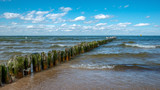Fototapeta  - spokojne morze Bałtyckie zalewa słoną wodą drewniane pale ochronne. Międzyzdroje, Polska