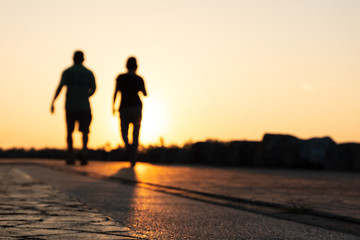 Silhouette of young couple runner are running in park at evening sunset.