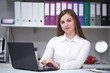 Portrait of beautiful brunette girl working in office behind laptop on desk