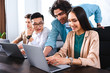 © LIGHTFIELD STUDIOS - smiling multicultural group of business colleagues having meeting at table with laptops in modern office