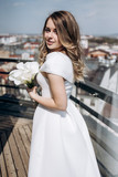 Fototapeta Londyn - The charming bride looking at city and standing on the ballcony