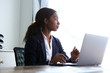 © mimagephotos - young african businesswoman sitting at her desk with a laptop