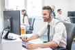 © Bojan - Handsome man in business wear with headset using computer in call center