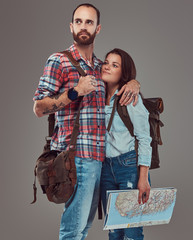 Happy couple of tourists with backpack and map, cuddling in a studio.