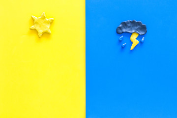 Good and bad weather concept. Template for forecast. Sun vs cloud and lightening with rain on yellow and blue background top view copy space