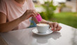 Woman hand pouring a sugar packet into a cup of coffee.