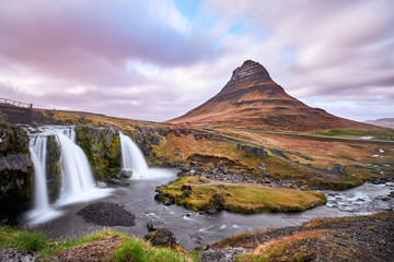  Summer sunset over the famous Kirkjufellsfoss Waterfall with Kirkjufell mountain in the background in Iceland. Long exposure HDR. May 2018.