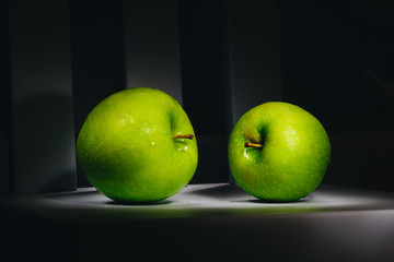 two fresh green apples on a dark background.