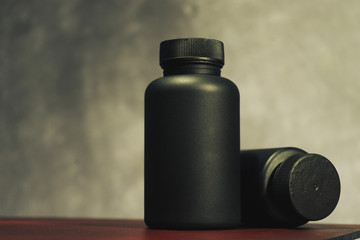 Poster - Black Bottle for pills on a red glass table. Beautiful dark background.