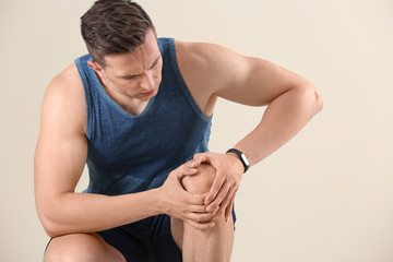 Sticker - Man in sportswear suffering from knee pain on light background