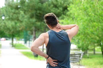 Man in sportswear suffering from back pain outdoors