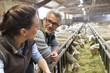 © goodluz - Couple of breeders in barn looking at sheep herd