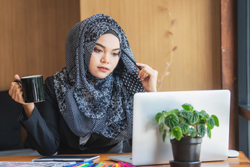 Leinwandbilder - Young muslim asian female designer using graphics tablet while working with computer at studio or office.	