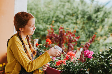 Adorable little girl watering plants on the balcony on a nice sunny day