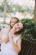 © Tetiana - Beautiful young woman with her little daughter relaxing on bench in summer park