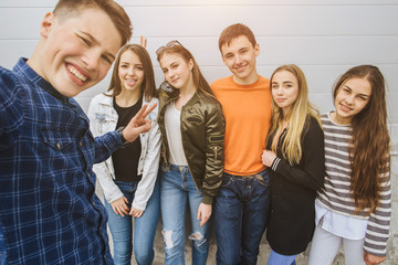 Summer holidays and teenage concept - group of smiling teenagers with skateboard hanging out outside and makes selfie.