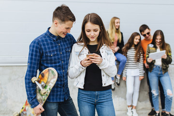 Summer holidays and teenage concept - group of smiling teenagers with skateboard hanging out outside.