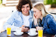 © Alvin Harambašić - Young cheerful couple using headphones and smartphone for fun while sitting in cafe's garden