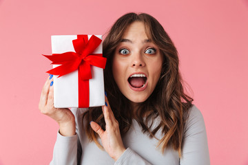 Shocked young pretty woman holding surprise gift present box.